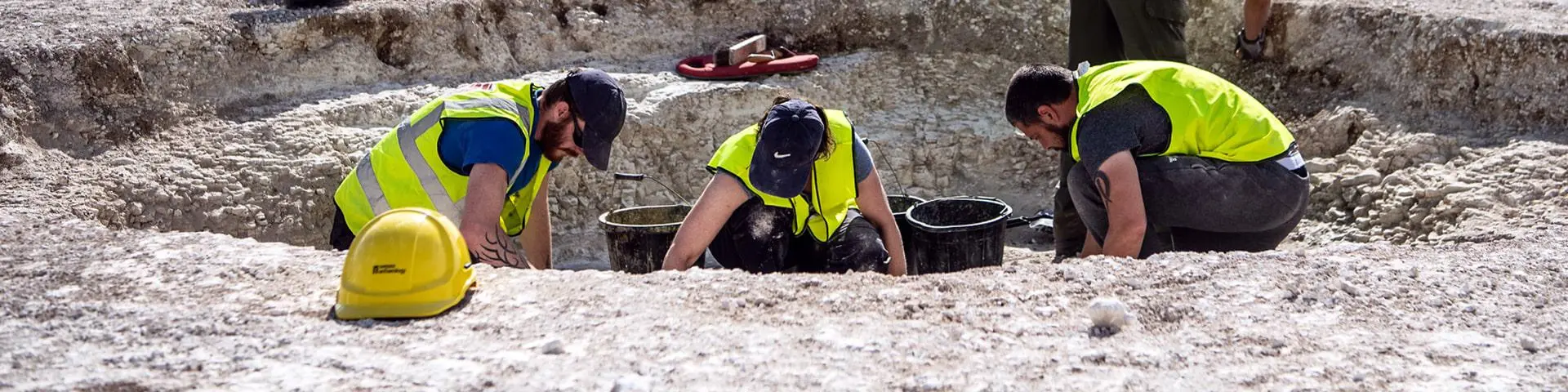 Three people excavating on an archaeological dig