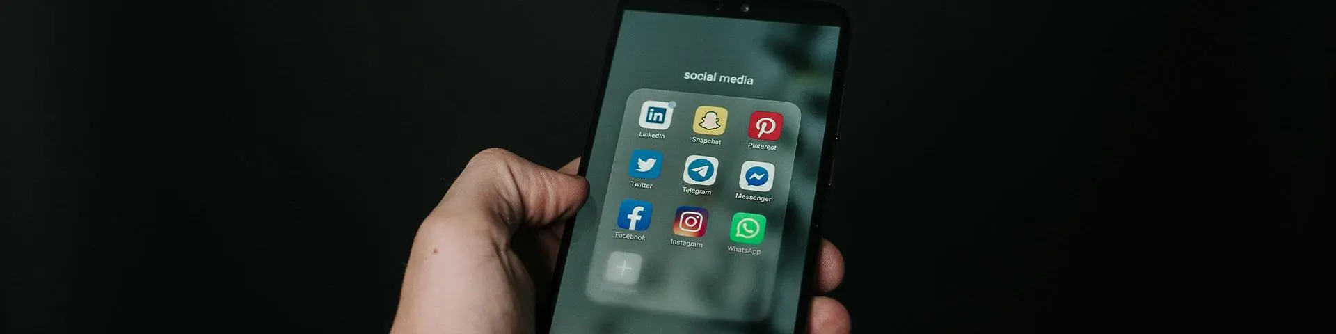 A person holding a phone which shows icons for social media apps.