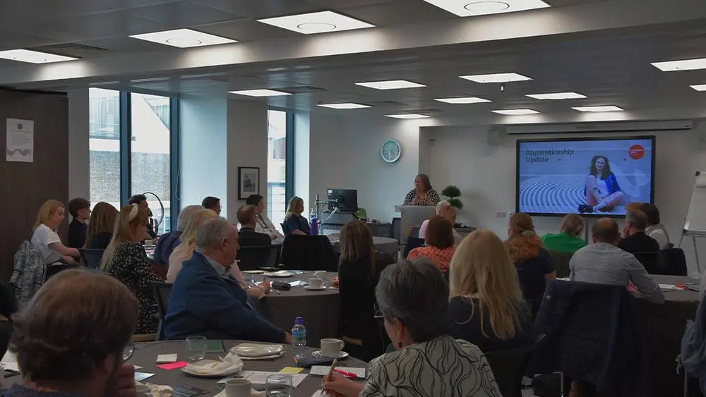 A room full of people listening to Cathy Barnes speak.