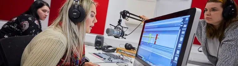 A journalism student sat in front of a camera and behind a green screen